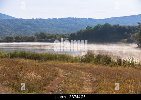 Paesaggio estivo costiero. Lago foggy in Crimea montagne al sole mattina d'estate sotto cielo nuvoloso Foto Stock