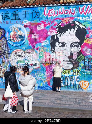 PRAGA-Marzo 13:nonostante Covid-19 restrizioni di viaggio di gov ceco., i turisti ancora vengono da tutto il mondo. Turisti che scattano foto con Lennon´s Foto Stock