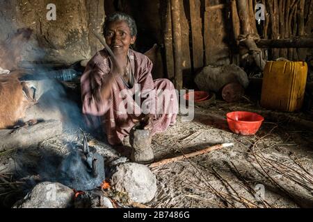 Villager che batte i chicchi di caffè usando un mortaio e pestello, Monti Simien, Etiopia Foto Stock