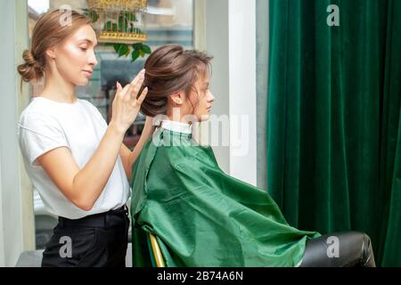 Parrucchiere professionale rendendo l'acconciatura per donna in un salone di bellezza. Foto Stock