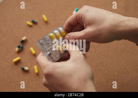 Primo piano delle mani maschili che detengono la medicina e lui li beve dalla malattia Foto Stock