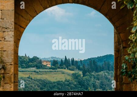 Una vista sulla campagna toscana attraverso porta Fiorentina, la porta occidentale della fortezza di Monteriggioni, in Toscana, in maggio. Foto Stock