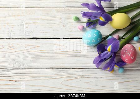 Composizione con uova di Pasqua e fiori di Iris su sfondo di legno, spazio per il testo Foto Stock