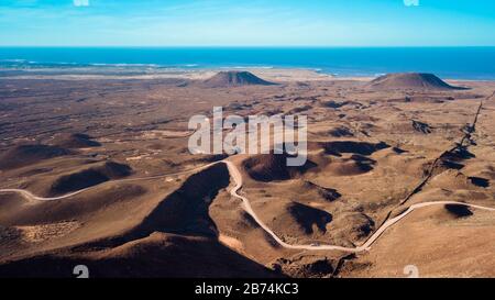 Veduta aerea di una strada che conduce attraverso una vasta area di terra vulcanica e montagne Foto Stock