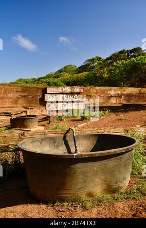 Cartello "The Watering Hole" e grande secchio d'acqua per cavalli vicino recinto e Corral, stalla, a 900 acri di gunstock Ranch, Oahu Island, Laie, Hawaii, USA Foto Stock