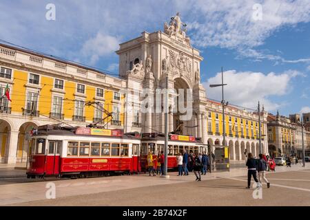 Lisbona, Portogallo - 2 marzo 2020: Due tram rossi 28 alla Praca do Comercio di fronte all'Arco da Rua Augusta Foto Stock