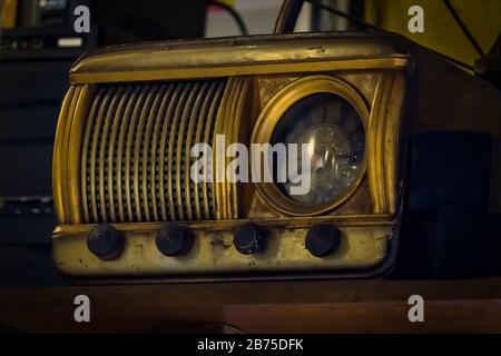 Vecchio ricevitore radio vintage del secolo scorso con orologio rustico costruito in, su scaffale, vista frontale. Messa a fuoco selettiva e fotografia di stile grungy Foto Stock