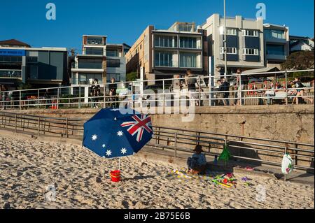 21.09.2018, Sydney, nuovo Galles del Sud, Australia - UNA donna siede a Bondi Beach sotto un ombrellone con la bandiera nazionale australiana stampata su di esso. [traduzione automatica] Foto Stock