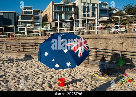 21.09.2018, Sydney, nuovo Galles del Sud, Australia - UNA donna siede a Bondi Beach sotto un ombrellone con la bandiera nazionale australiana stampata su di esso. [traduzione automatica] Foto Stock