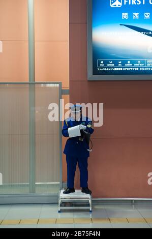 23.12.2017, Osaka, Giappone, Asia - UN dipendente aeroportuale in uniforme si trova su una piccola piattaforma all'Aeroporto Internazionale di Kansai e prende appunti. [traduzione automatica] Foto Stock