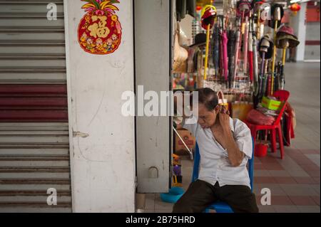 19.02.2018, Singapore, Repubblica di Singapore, Asia - un uomo anziano siede su una sedia nel centro commerciale Chinatown Complex nel quartiere Chinatown di Singapore, prendendo un pisolino. [traduzione automatica] Foto Stock