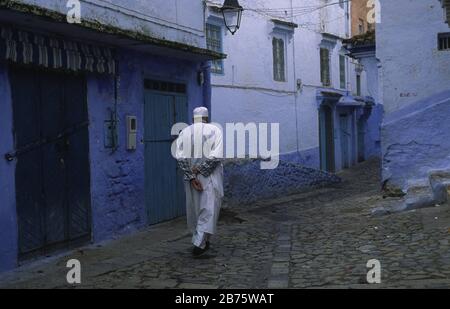 18.11.2010, Chefchaouen, Marocco, Africa - UN uomo cammina attraverso vicoli tortuosi e lungo le facciate dipinte di bianco e blu nella medina di Chefchaouen. [traduzione automatica] Foto Stock