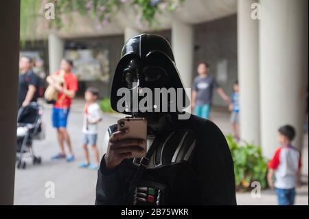 06.05.2017, Singapore, Repubblica di Singapore, Asia - UNA donna in un costume di Darth Vader sta usando il suo smartphone durante l'evento annuale di Star Wars nel boschetto dei Supertrees a Gardens by the Bay. [traduzione automatica] Foto Stock