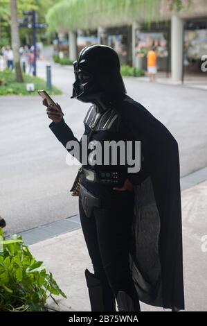 06.05.2017, Singapore, Repubblica di Singapore, Asia - UNA donna in un costume di Darth Vader sta usando il suo smartphone durante l'evento annuale di Star Wars nel boschetto dei Supertrees a Gardens by the Bay. [traduzione automatica] Foto Stock