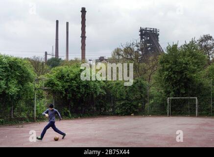 Un ragazzo gioca a calcio su un campo di cenere a Duisburg-Marxloh presso lo stabilimento di ThyssenKrupp Schwelgern il 21 aprile 2017. Con un tasso di disoccupazione del 13%, gennaio 2017, e una quota di stranieri di quasi il 20%, la città di Duisburg sta affrontando grandi problemi sociali. [traduzione automatica] Foto Stock