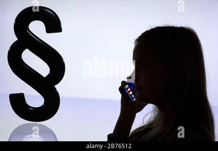 La silhouette di una donna con uno smartphone in mano è visibile di fronte al logo Paragrapen, su 12.01.2016. Consultazione telefonica in materia legale. [traduzione automatica] Foto Stock