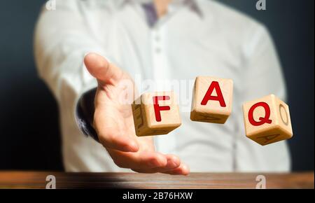 Cubi gettati da un uomo fare parola abbreviazione acronimo FAQ (domande frequenti). Pratica forma di risposte per gli utenti e i clienti Foto Stock