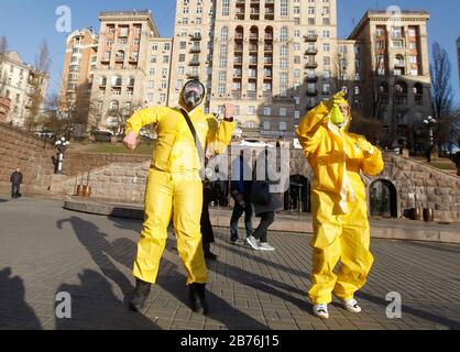 Kiev, Ucraina. 13 Marzo 2020. Le persone che indossano costumi protettivi ballano mentre prendono parte a un flashmob contro il coronavirus COVID-19 in una strada nel centro di Kiev, Ucraina, il 13 marzo 2020. L'Ucraina chiuderà il confine per gli stranieri in 48 ore per due settimane a causa della situazione con il coronavirus COVID-19 diffuso nel mondo, il Segretario del Consiglio Nazionale di sicurezza e Difesa dell'Ucraina Oleksiy Danilov ha detto il 13 marzo 2020. Credit: Serg Glovny/Zuma Wire/Alamy Live News Foto Stock