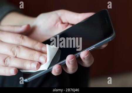 Pulire e disinfettare il telefono cellulare. Germi, batteri, contaminazione Covid-19 Foto Stock
