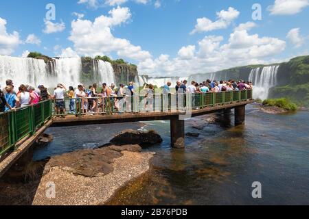 I turisti che si godono le cascate di Iguaçu, in Brasile, dalla passerella sopra l'acqua. Bellissimo paesaggio naturale nella foresta del Sud America con numerose cascate Foto Stock