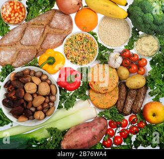 Cibo vegano, tra cui pane, verdure, frutta fresca, hamburger e salsicce vegane, hummus, quinoa, fagioli, piselli, legumi, pasta, frutta secca e noci. Foto Stock