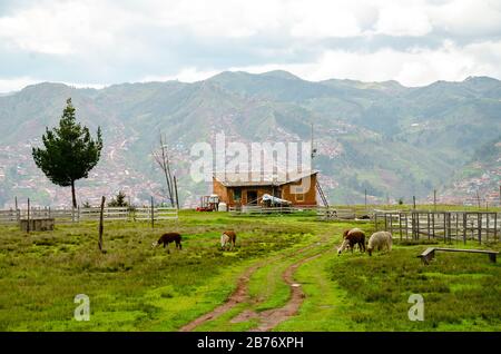 Cusco, Perù; 24 gennaio 2017: Vecchia casa sulla cima di una collina con vista sulla città di Cusco e le montagne nuvolate Foto Stock