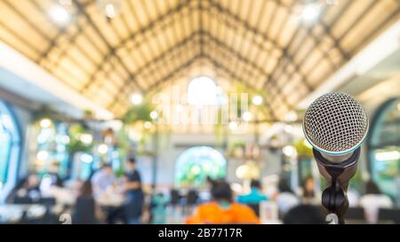 Microfono sopra l'astratto offuscato di passaggio nella sala seminari o sala conferenze luce sullo sfondo del ristorante, business e concetto di istruzione. Foto Stock