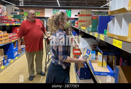 Bloomington, Stati Uniti. 13 Marzo 2020. Una donna raccoglie il cibo dopo gli acquirenti panico acquistare cibo in un negozio di alimentari Aldi a Bloomington.La donna sulla destra ha detto: "Ho tre figli, devo fare quello che ho da fare." il presidente degli Stati Uniti Donald J. Trump ha dichiarato un'emergenza nazionale solo ore prima. Credit: Sopa Images Limited/Alamy Live News Foto Stock