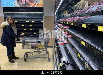 Bloomington, Stati Uniti. 13 Marzo 2020. Gli scaffali di carne sono vuoti dopo che gli acquirenti di panico comprano cibo in un negozio di alimentari Aldi Bloomington.La donna sulla destra ha detto: "Ho tre figli, devo fare quello che devo fare." il presidente degli Stati Uniti Donald J. Trump ha dichiarato un'emergenza nazionale solo ore prima. Credit: Sopa Images Limited/Alamy Live News Foto Stock