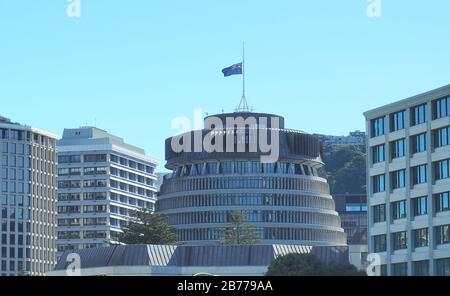 Il Beehive, il parlamento neozelandese di Wellington, vola la bandiera a metà albero nel primo anniversario della sparatoria della moschea di Christchurch del 2019. Foto Stock