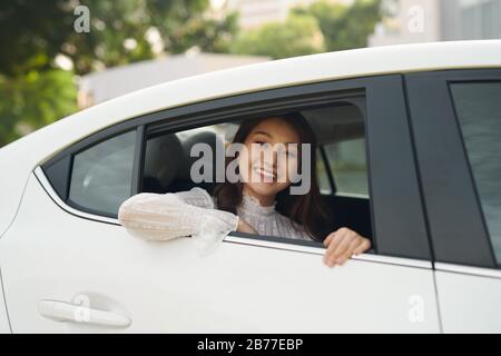 Bella giovane donna, guarda fuori dalla finestra una macchina bianca Foto Stock