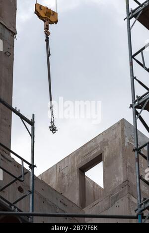 Ganci per gru e ponteggi davanti a un edificio incompiuto Foto Stock