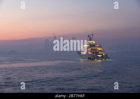 Palm Jumeirah, Dubai, Emirati Arabi Uniti - Mar 13, 2020: Colori dell'alba sul Dubai Jumeirah disctrict paesaggio urbano e uno yacht parcheggiato in una giornata frizzante. Foto Stock