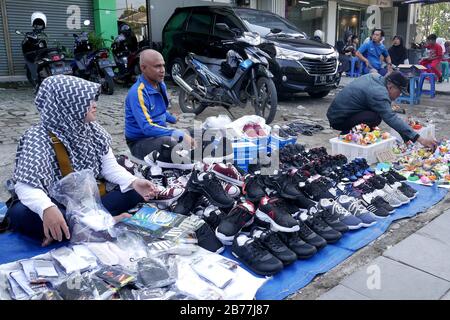 Street sellers and their merchandise in front of a parking lot. Foto Stock
