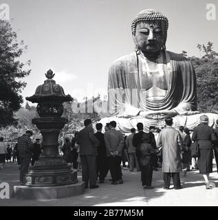 Anni '50, storico, i visitatori della sacra statua di bronzo, il Grande Buddha di Kamakura, Giappone, che si erge sui terreni del Tempio di Kotoku-in e un punto di riferimento storico nel paese risalente al 1252. Foto Stock
