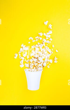 Popcorn sparso su uno sfondo giallo. Astrazione e minimalismo. Foto Stock
