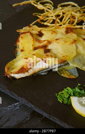 ​​bream di mare in crosta di patate con cipolla tritata fritta - colpo verticale studio Foto Stock