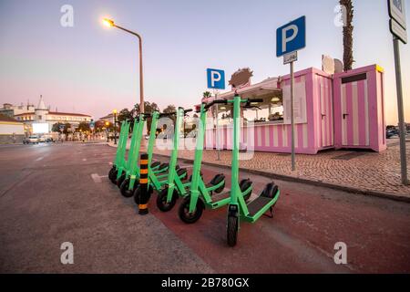 Scooter elettrici verdi in affitto parcheggiati in città. Foto Stock