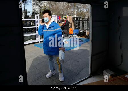 (200314) -- PECHINO, 14 marzo 2020 (Xinhua) -- li Jie contatta un cliente per telefono al Beijing Youth Politics College di Pechino, capitale della Cina, 12 marzo 2020. Li Jie, un deliveryman di ZTO Express, lavora nel settore della consegna espressa da 11 anni. Invece di tornare a casa nella Nuova Area di Xiong'an, nella provincia di Hebei della Cina settentrionale, ha soggiornato a Pechino e ha lavorato durante l'ultima festa di Primavera. Dopo lo scoppio del COVID-19, la gente preferisce rimanere nel paese per impedire la diffusione del coronavirus; intanto gli ordini in linea aumentano e i deliverymen ottengono molto occupati. Come membro di Foto Stock