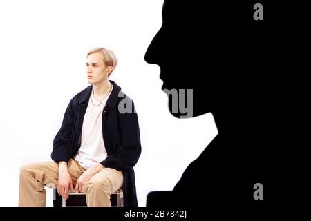 Silhouette del profilo di una donna. Un uomo è seduto su una sedia. Entrambi guardano nella stessa direzione. Isolamento foto. Foto Stock