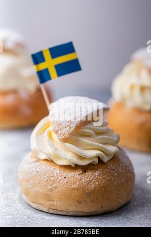 Semla, fastelavnsbolle, fastlagsbolle. Un tradizionale panino scandinavo ripieno di cardamomo con pasta di mandorle. Decorato con una bandiera svedese. Su un w Foto Stock