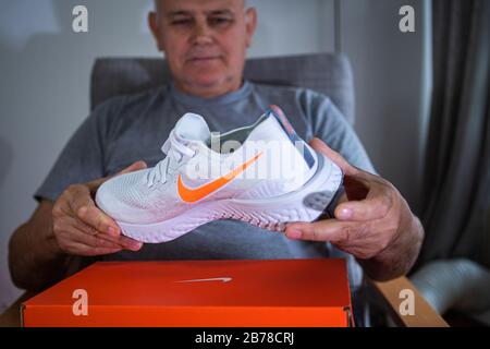 Parigi, Francia - 8 luglio 2019: Happy Senior Male mani in mano nuove Nike Flyknit React professionale running scarpe durante il disboxing Foto Stock