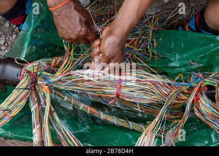 Tecnico che ripara una linea telefonica sotterranea con fili multicolore Foto Stock