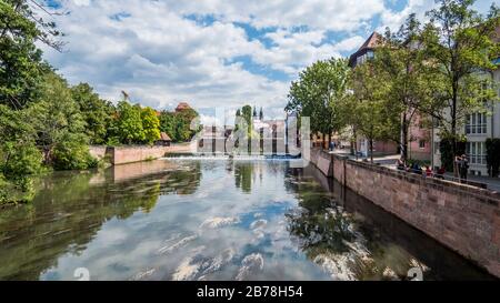 Norimberga 2019. Ponte massimo sul fiume Pegnitz visto tra gli alberi e le rive. Siamo in una giornata estiva soleggiata ma nuvolosa. Agosto 2019 a Nuremb Foto Stock