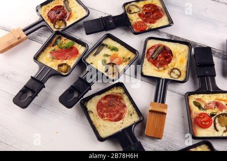 Delizioso formaggio svizzero tradizionale di raclette fuso su patate  bollite a dadini o al forno servito in abilità individuali con salame e  patate Foto stock - Alamy