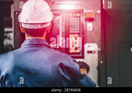 il lavoratore di fabbrica di closeup aziona la macchina, lavoro di alta abilità industria con vestiti di sicurezza. Foto Stock