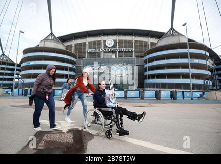 Persone al di fuori dell'Etihad Stadium, sede del Manchester City Football Club, dopo l'annuncio di ieri che la Premier League ha sospeso tutte le partite fino a sabato 4 aprile 2020. Foto Stock