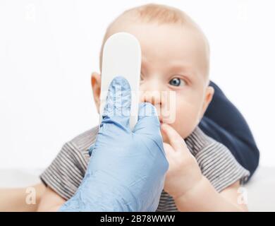 Il pediatra o l'infermiere controlla la temperatura corporea del bambino utilizzando un termometro frontale a infrarossi (termometro a pistola) per verificare l'eventuale presenza di sintomi di malattia Foto Stock