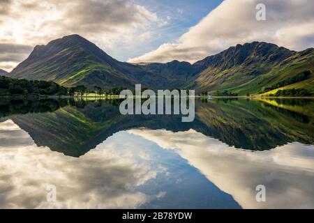 Le vette prominenti delle pile di Fleetwith Pike e Hay si riflettono nelle acque calme speculari di Buttermere in una mattina ferma all'inizio dell'autunno. Foto Stock