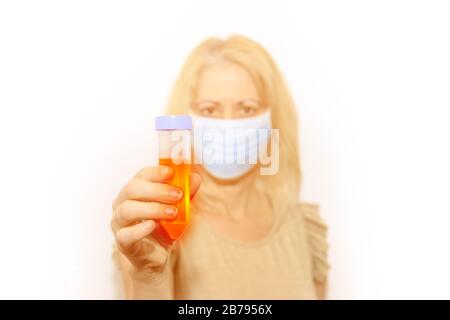 Donna ricercatore con maschera facciale con una luminosa provetta. Concetto di epidemia, quarantena per coronavirus e infezioni batteriche, test del virus e. Foto Stock